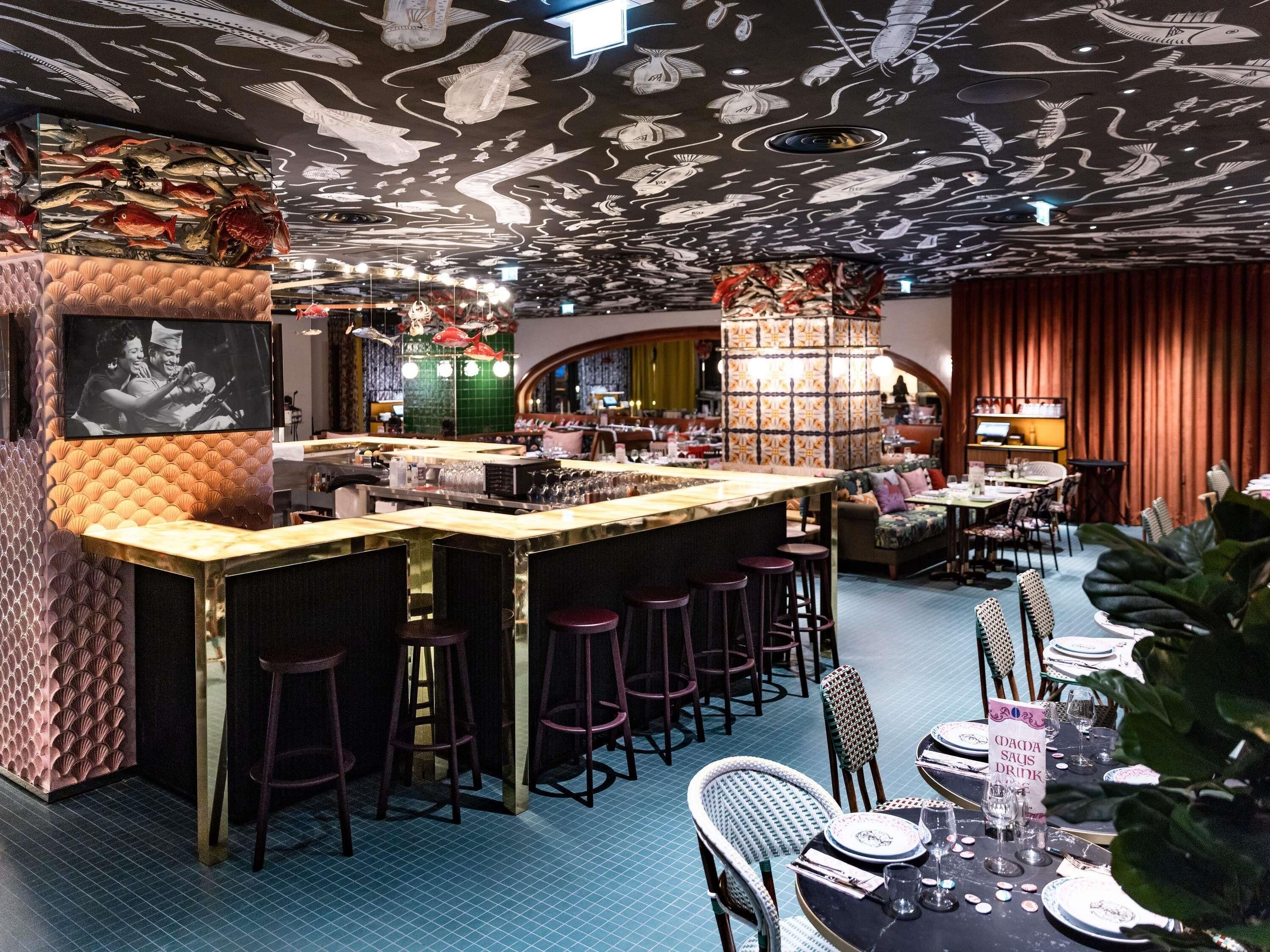 A bar area with stools, a counter, and a television screen.