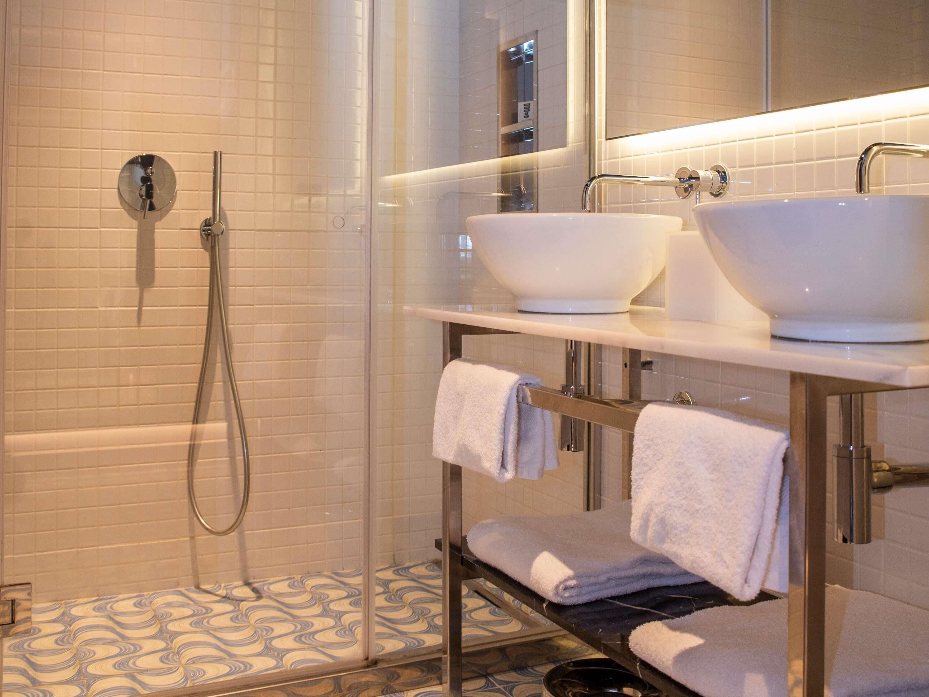 Une salle de bain moderne avec une douche à parois de verre, un meuble-lavabo à deux vasques et un carrelage décoratif.