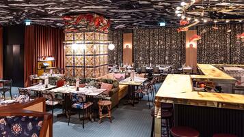 A restaurant with a ceiling decorated with fish patterns, tables with chairs, and a bar area.