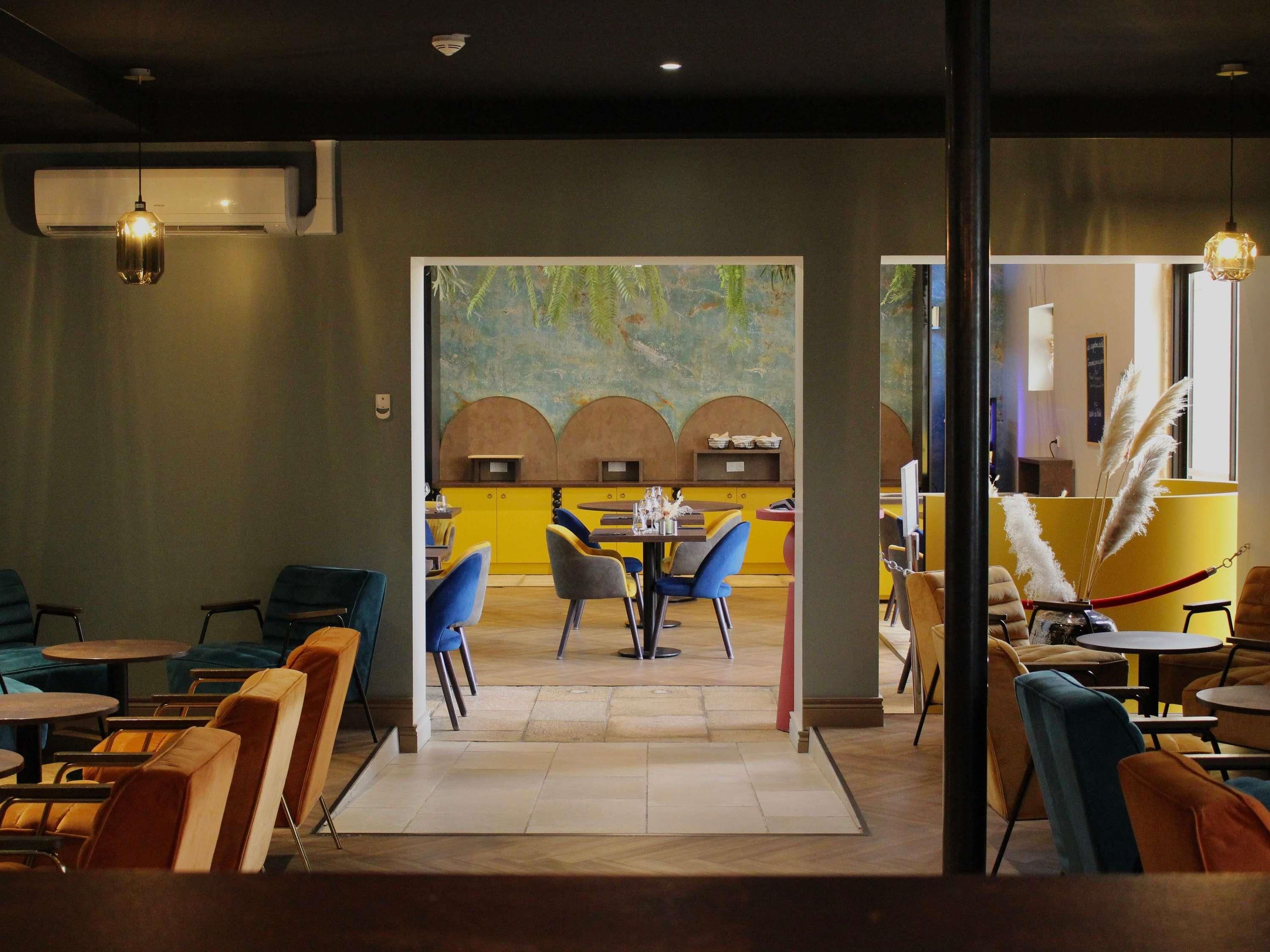 A restaurant interior with a central dining area, booths, and a bar area with yellow accents.