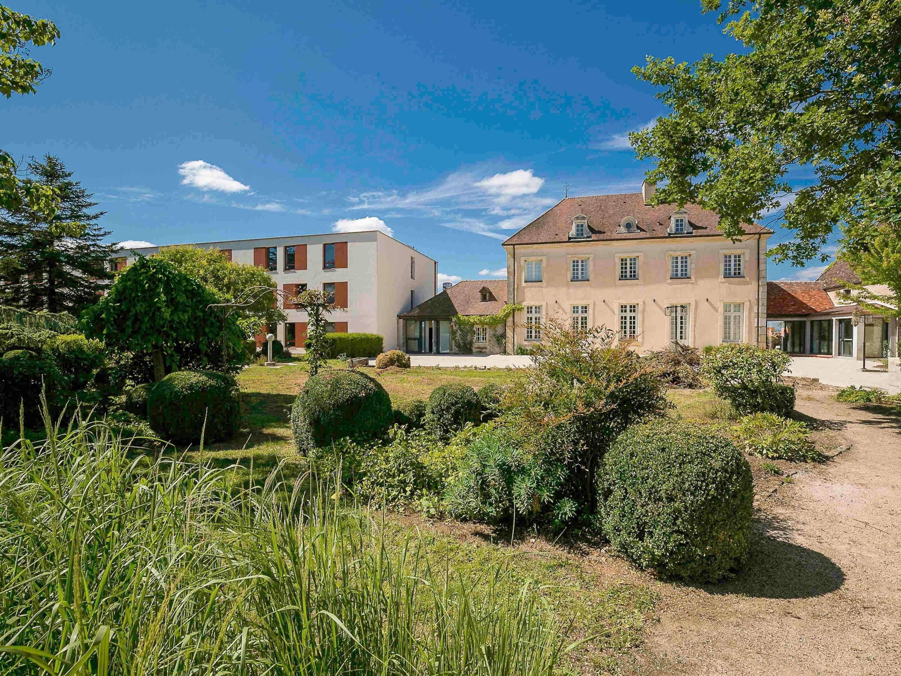 A residential area with modern buildings, well-maintained gardens, and a clear sky.