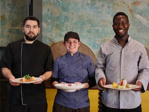 Three individuals holding plates of food in a room with a textured wall. - ibis styles Dijon Sud Domaine de Beauregard (Longvic)
