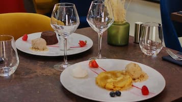 Una mesa de comedor con platos de postres, copas de vino vacías y un florero con flores secas.
