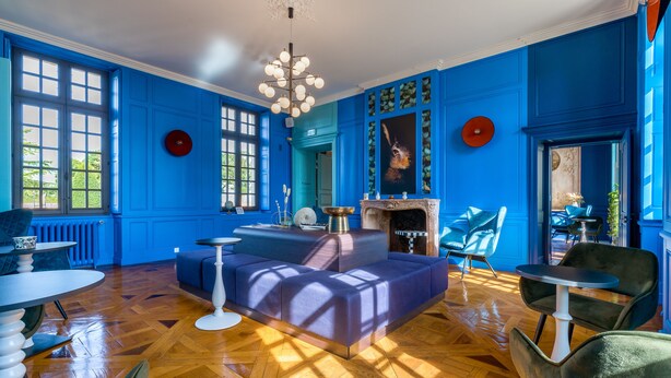 A room with blue walls, a fireplace, and a large window.