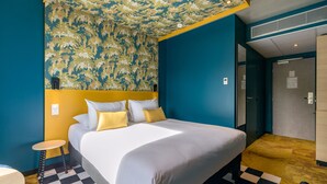 A hotel room with a bed, a small round table, a checkered rug, and a patterned ceiling.