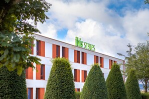 A modern building with a sign reading "Ibis Styles." It features a white facade with red accents and multiple windows. - ibis styles Dijon Sud Domaine de Beauregard (Longvic)