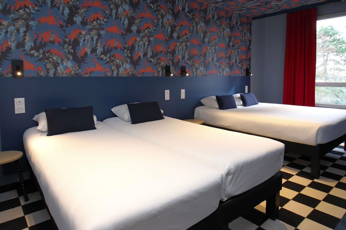 Een hotelkamer met twee bedden, een geruite vloer en een wand met bloemenprint.