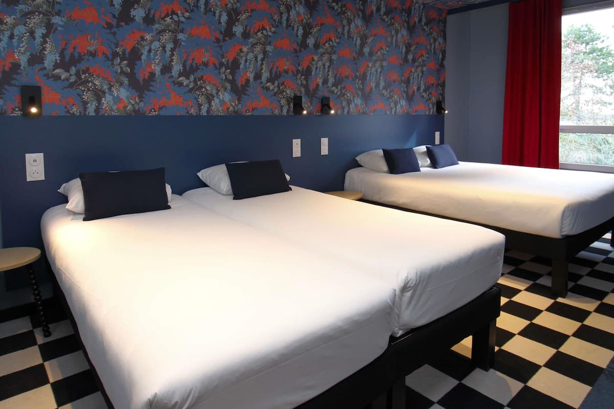 Una habitación de hotel con dos camas, piso a cuadros y un papel tapiz con motivos florales.