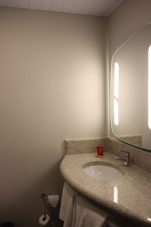 Un baño con lavamanos de encimera de granito, un espejo y un inodoro.