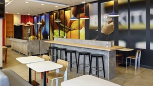 Un intérieur de restaurant moderne avec des tables blanches, des tabourets de bar noirs et des luminaires suspendus.