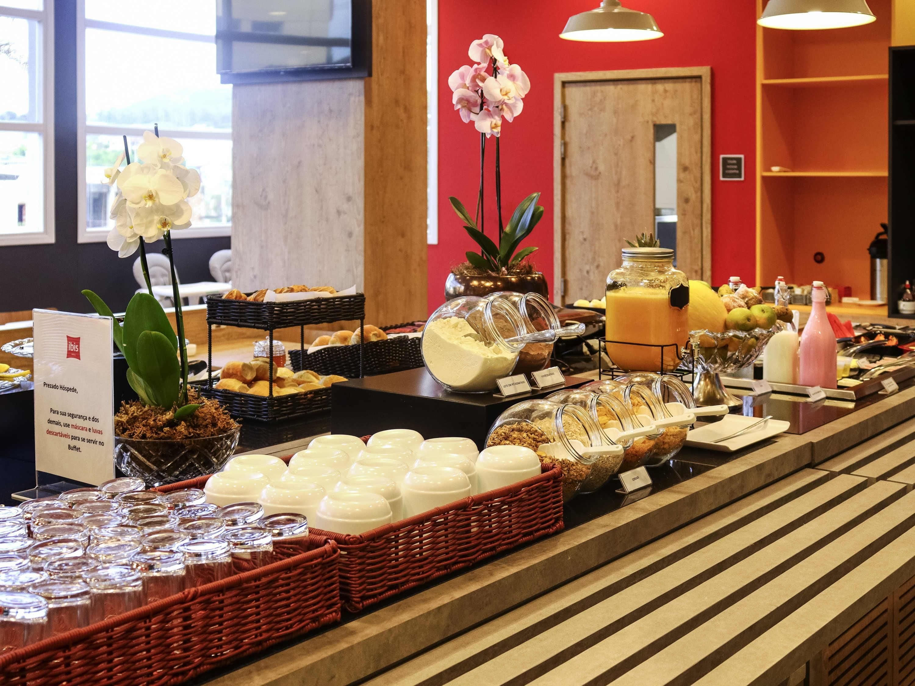 A buffet setup with various food items, including pastries, fruits, and beverages, arranged on a counter with baskets and containers.