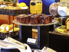 A display of chocolate desserts on a glass stand with a sign reading "Bolo de Chocolate". - Ibis Guaxupe (Guaxupé)