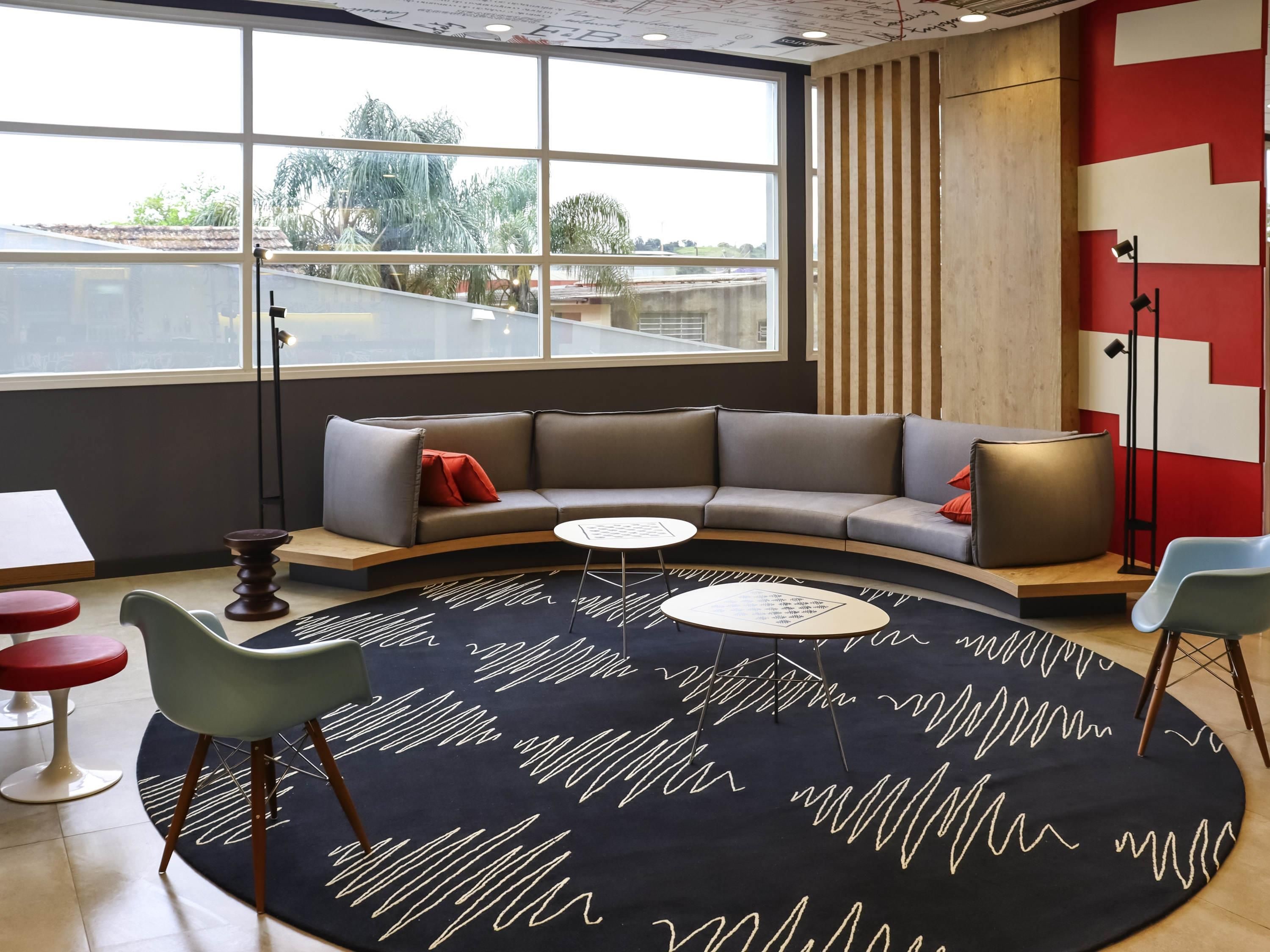 Et moderne loungeområde med en buet sofa, et rundt sofabord og et tæppe med et mønster.