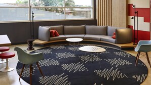 Un espace de détente moderne avec un canapé incurvé, une table basse ronde et un tapis à motifs.