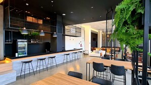 A modern bar area with a counter, stools, and a seating area with tables and chairs. -  Serrana Residence Hotel  (Nova Serrana)