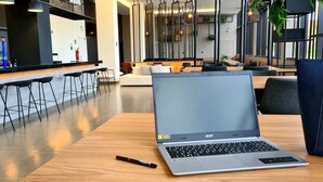 A modern cafe with a laptop on a table, bar stools, and a sofa in the background. -  Serrana Residence Hotel  (Nova Serrana)