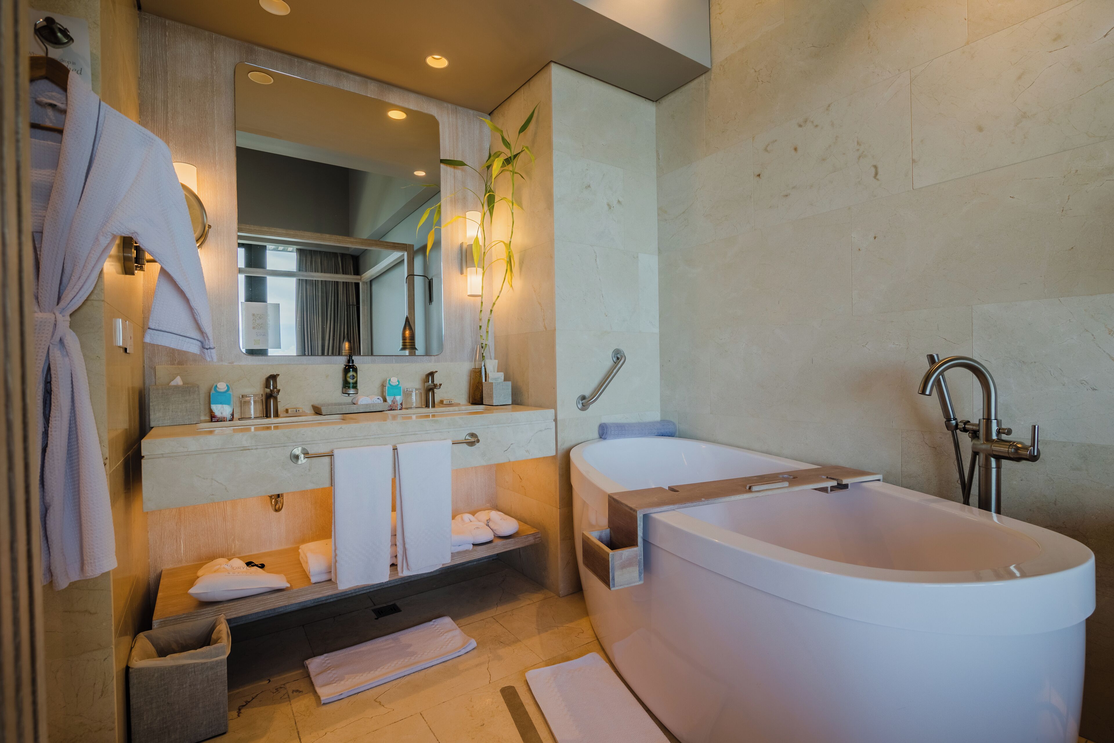 A modern bathroom with a large bathtub, a double sink vanity, and a mirror above the vanity.