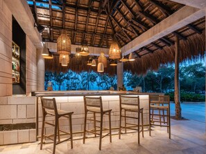 A bar area with wicker chairs, a thatched roof, and a view of the ocean. - Sofitel Barú Cartagena (Cartagena)