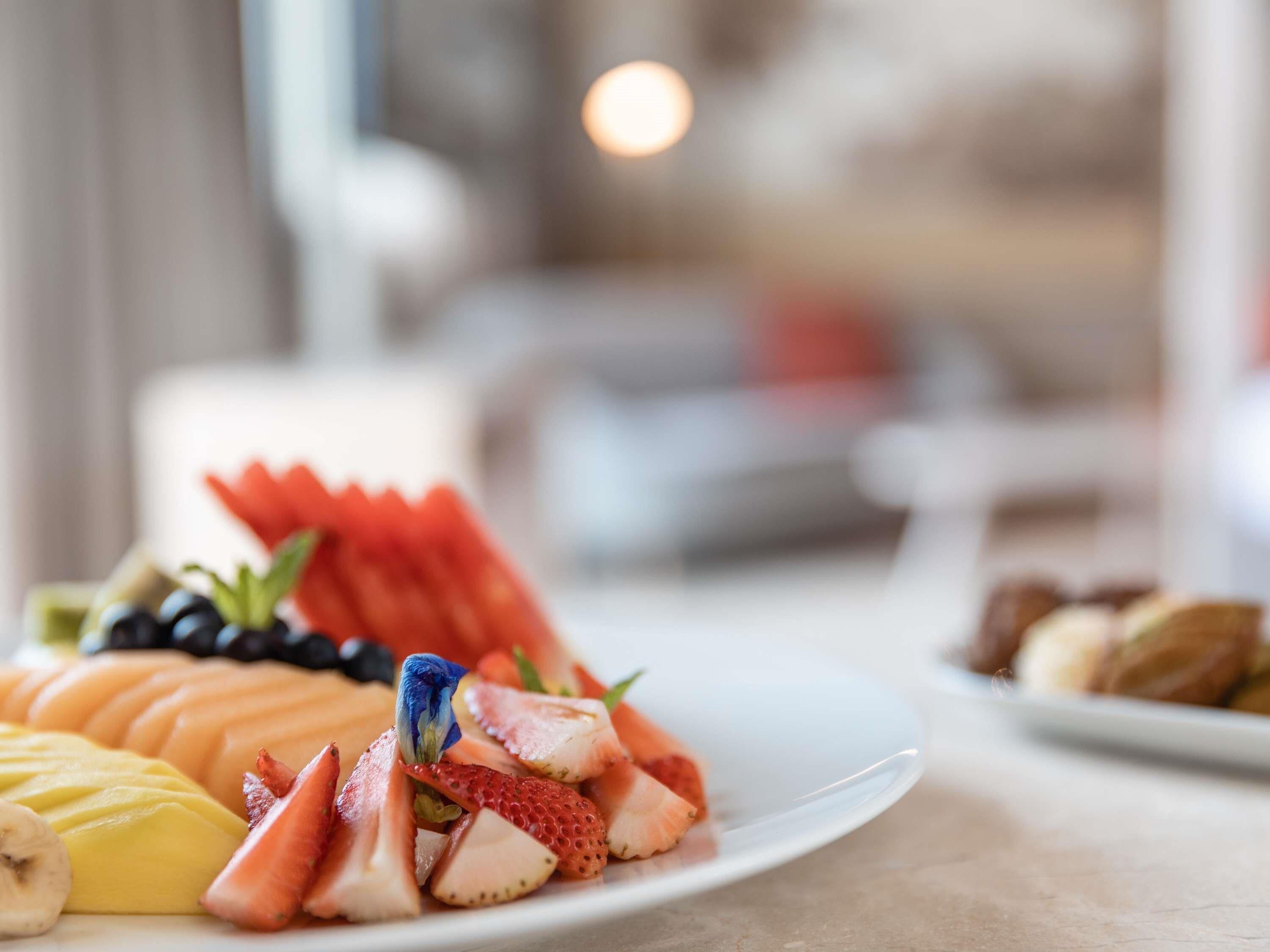 A plate of assorted fruits including melon, strawberries, and bananas.
