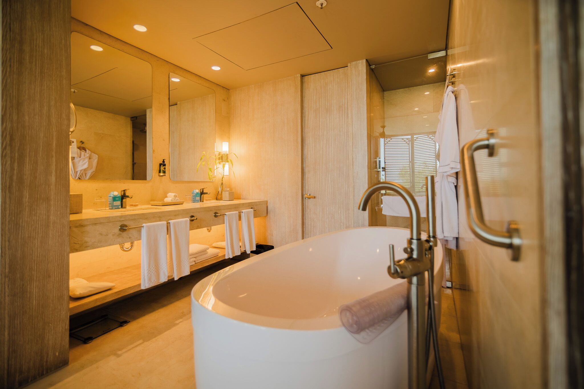 Een moderne badkamer met een vrijstaand bad, een grote spiegel en een wastafel met een handdoekhouder.