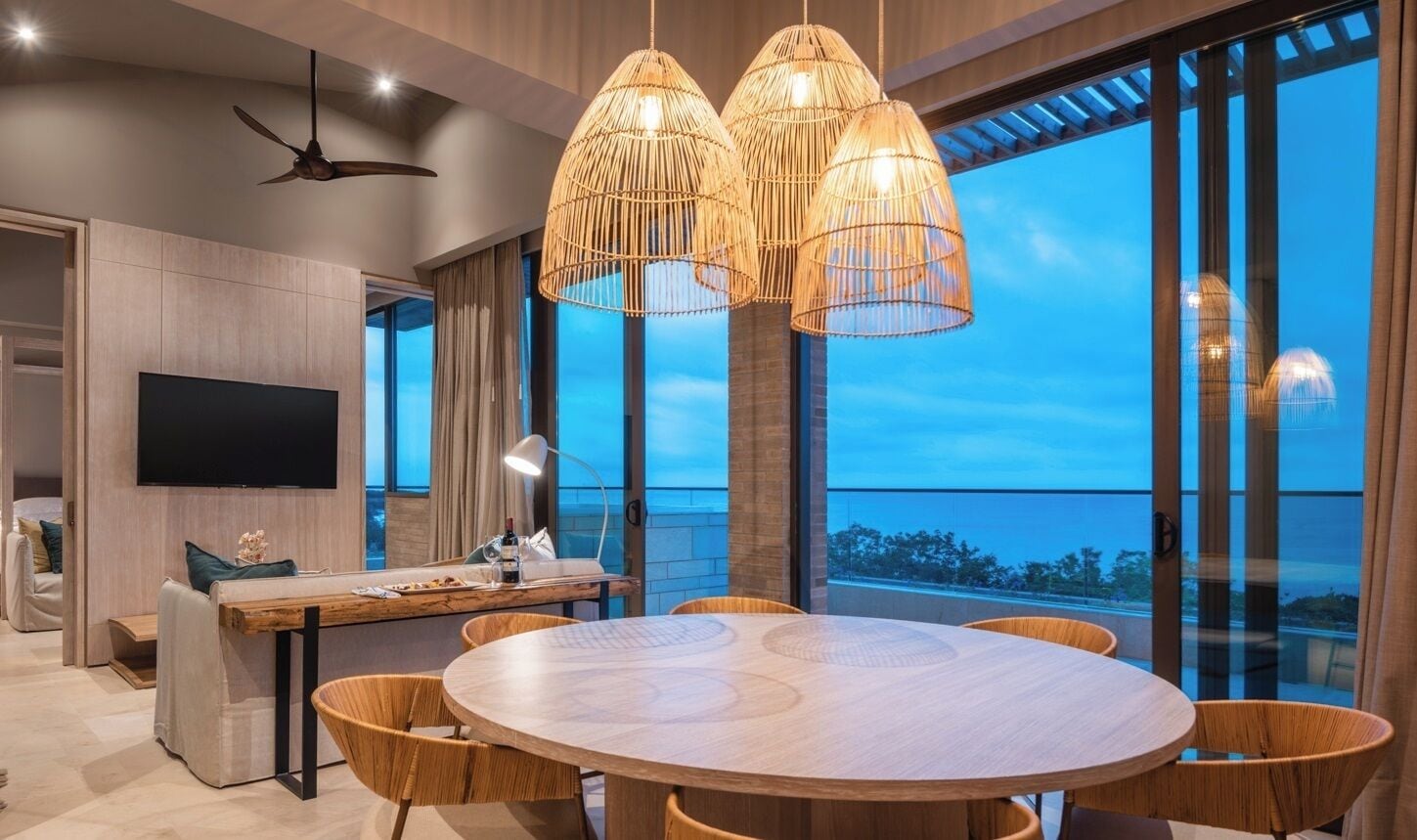 A modern dining area with a round table and chairs, large windows with a view, and a ceiling fan.