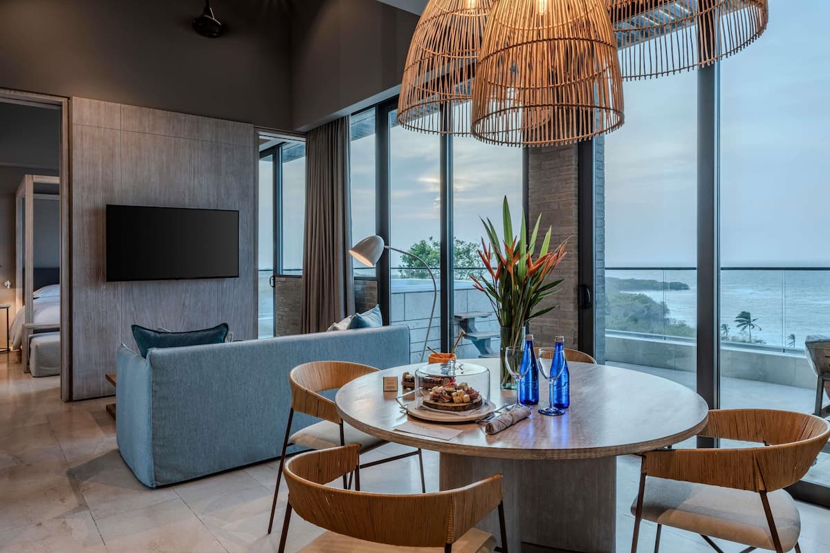 A modern living room with a large window, a round dining table, and a sofa.