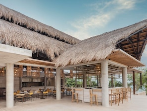 A restaurant with thatched roofs, outdoor seating, and a view of greenery. - Sofitel Barú Cartagena (Cartagena)