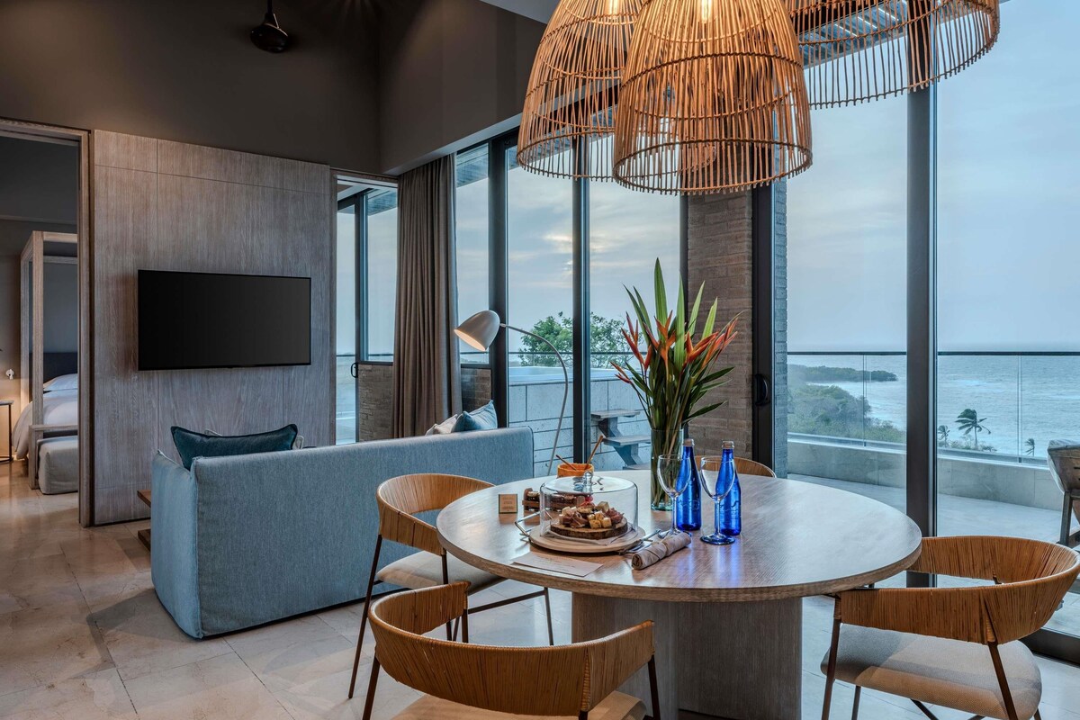 A modern living room with a large window, a round dining table, and a sofa.