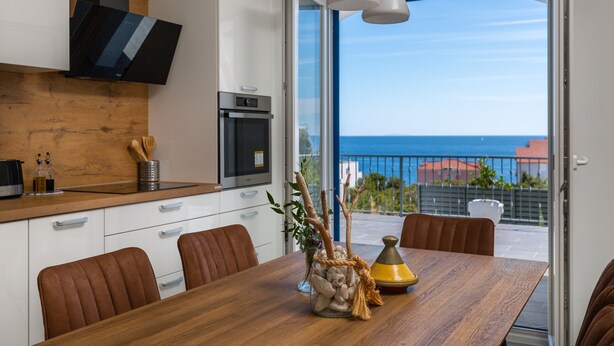 A modern kitchen with a wooden countertop, a built-in oven, and a dining area with a wooden table and chairs.