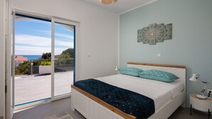 A bedroom with a bed, a view through a sliding door, a wall-mounted light, and a ceiling light.