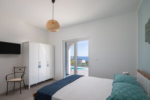A bedroom with a bed, a chair, a wardrobe, and a television.