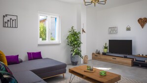 A modern living room with a sofa, coffee table, TV, and decorative items.