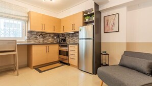 Una cocina moderna con armarios de madera, un refrigerador de acero inoxidable y un sofá gris.