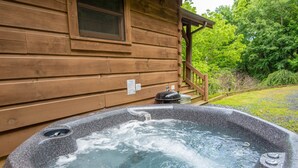 Una cabaña de madera con un jacuzzi en la parte delantera.
