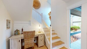 A staircase with white railings and wooden steps leading to a landing with a wicker chair and a small table. - Hickory Cove Villa Near Beach, Golf & Pickle Ball at Palmetto Dunes (Hilton Head)