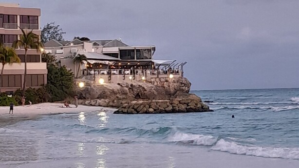 A coastal building with a restaurant on a rocky outcrop, overlooking the sea.