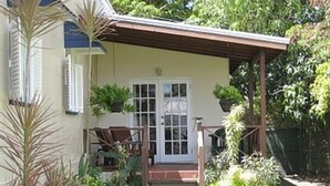 A house with a front porch, a door, and a small garden area with plants and a pathway.