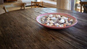 A dining area with a wooden table and a bowl of assorted nuts. There is a white sofa and a wooden cabinet in the background.