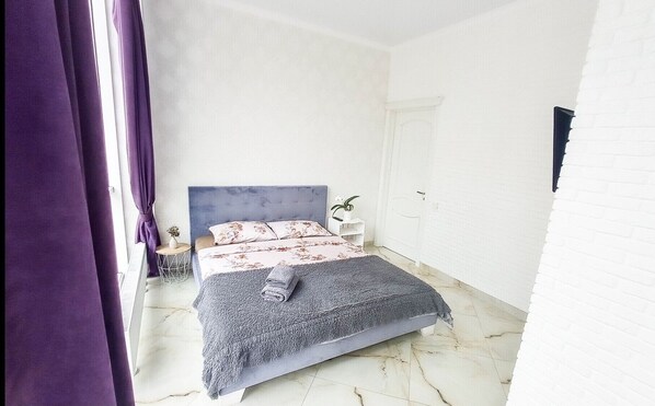 Cozy retreat with a plush bed, a small table, and a vase with a plant.