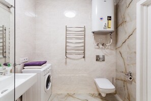 Bathroom features a washing machine, toilet, and towel rack.