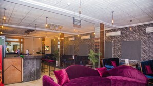 Een moderne lobby met een gebogen paarse bank, een bar en een marmeren wand.