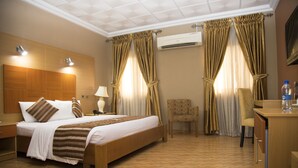 Hotelkamer met een bed, bureau, stoel, airconditioning en gordijnen.