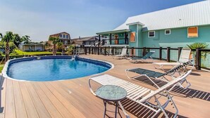 Una piscina con sillas de descanso y una terraza.