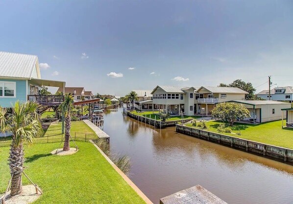 A canal with houses on either side, a bridge, and a small boat dock. - Beach House in the Bay! (Bay St. Louis)