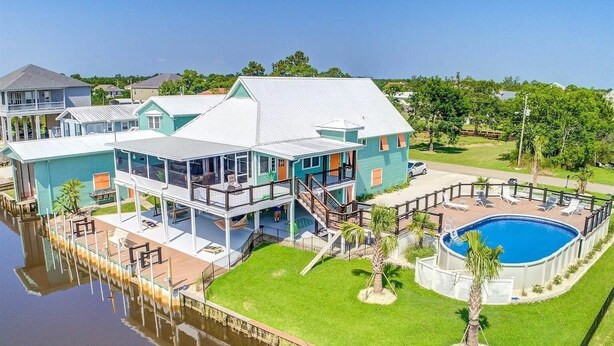 Una casa grande con varios niveles, una piscina y un muelle que se adentra en el agua.