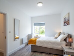 Une chambre à coucher avec un lit, des tables de chevet, une fenêtre et un tableau au mur.