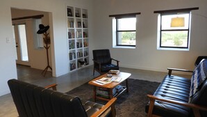 A living room with a sofa, armchairs, a coffee table, a bookshelf, and a window.