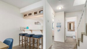 A modern kitchen with bar stools, a wooden counter, and a hanging sign. - Beautiful North Bluff Seascape Resort 2/2.5 Ocean View (Aptos)