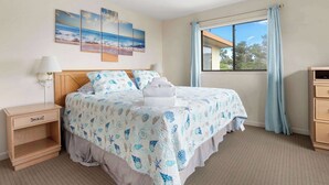 A neatly arranged bedroom with a bed, bedside tables, a window with curtains, and wall art. - Beautiful North Bluff Seascape Resort 2/2.5 Ocean View (Aptos)