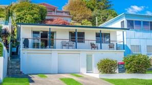 Un edificio residenziale su due piani con un balcone, un garage e un cortile anteriore.